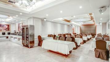 A banquet hall with multiple tables, chairs, and a buffet area.