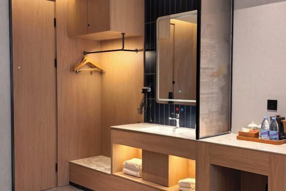 A modern bathroom with a wooden vanity, a mirror, and a towel rack.