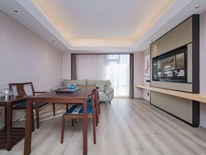 A hotel room with a dining area, a sofa, a TV, and a large window. - Vienna International Hotel (Wuhan Yellow Crane Tower Pengliuyang Subway Station) (Wuhan)