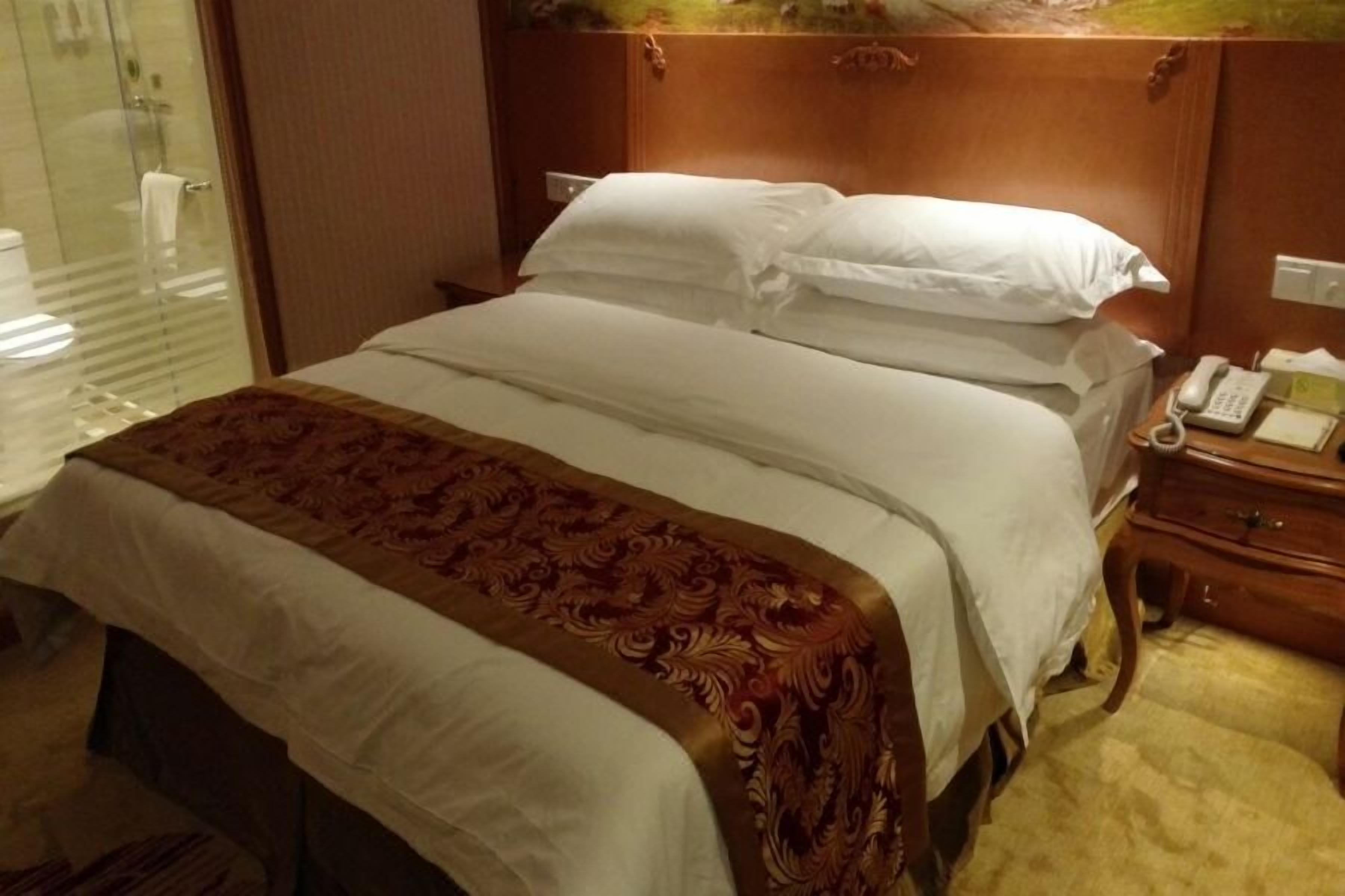 Una camera d'albergo con un letto, un comodino e un telefono.