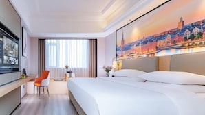 A hotel room with a large bed, a desk with a chair, a TV, and a cityscape painting on the wall. - Vienna International Hotel (Wuhan Yellow Crane Tower Pengliuyang Subway Station) (Wuhan)