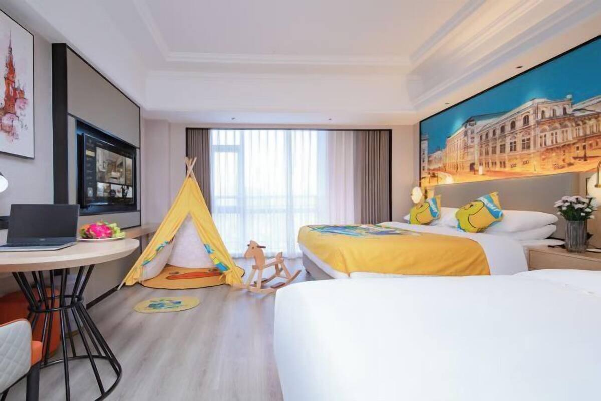 Une chambre d’hôtel avec un lit, un ordinateur portable, une tente et un tableau accroché au mur.