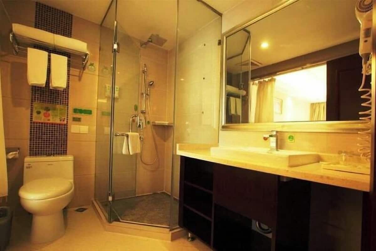 Une salle de bain moderne dotée d’une douche à parois de verre, de toilettes et d’un meuble-lavabo avec un miroir.