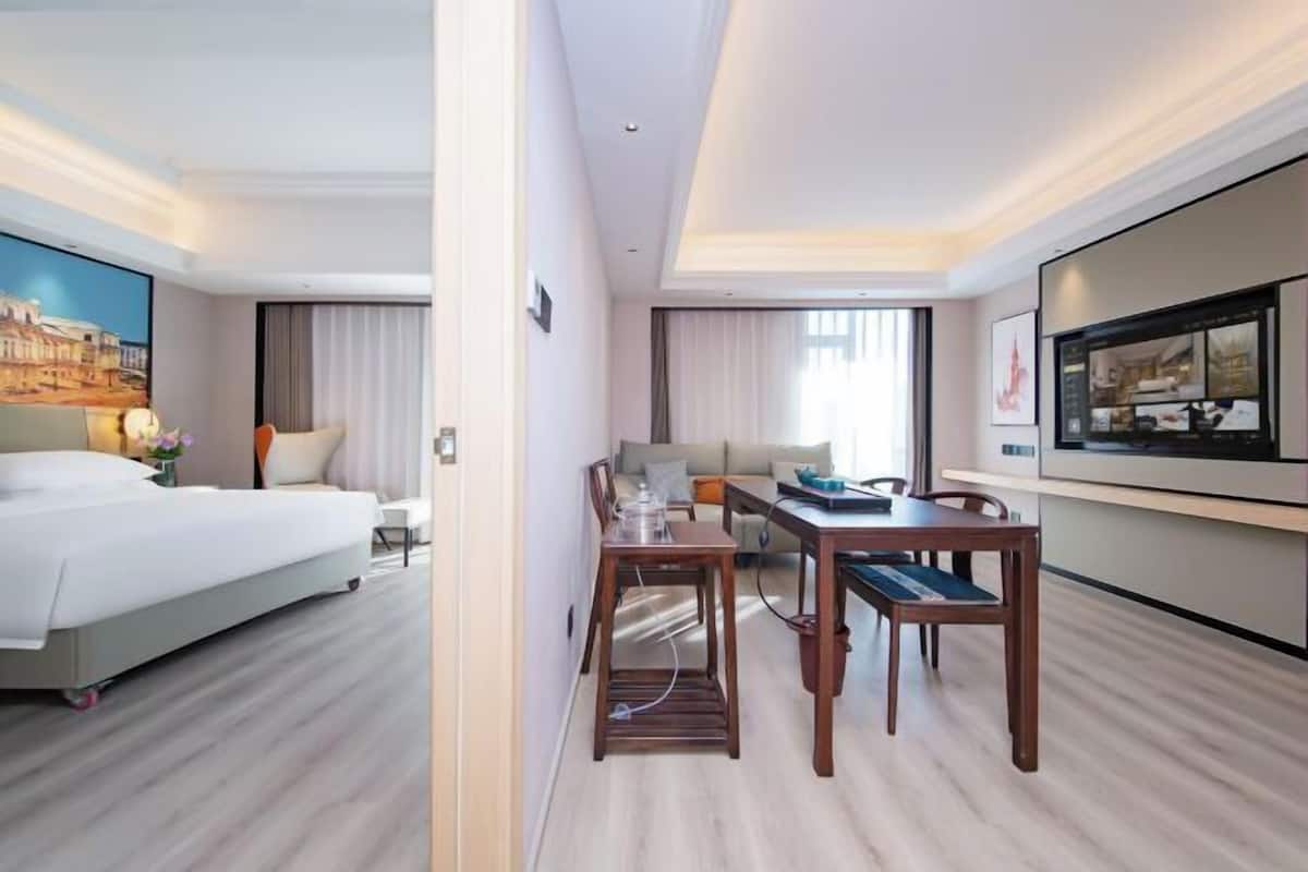 Une chambre d’hôtel avec un lit, une table à manger avec des chaises, un téléviseur et un tableau au mur.