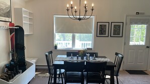 A dining area with a chandelier, a table with chairs, a window with a view of a deck, and a door labeled "MOUNTAIN TOP". - Cozy year round retreat! Close to skiing, hiking and swimming. (East Jewett)