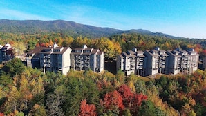 Un ensemble résidentiel comprenant plusieurs immeubles d’appartements, entouré d’un feuillage automnal et avec des montagnes en arrière-plan.