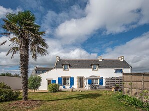 Traditional European-style house with a sloped roof and garden, featuring a patio area with outdoor seating.