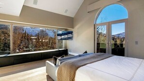 Un dormitorio con una cama grande, un área de descanso con vistas y una puerta corrediza a un balcón.