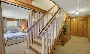 A wooden interior with a staircase, a bed, and a plant.