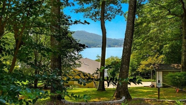 Ein ruhiges Anwesen am Seeufer, mit einem Haus, umgeben von hohen Bäumen und freiem Blick auf den See.