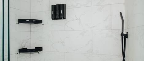 Un área de ducha moderna con ducha de color negro, ducha de mano y grifo empotrado.