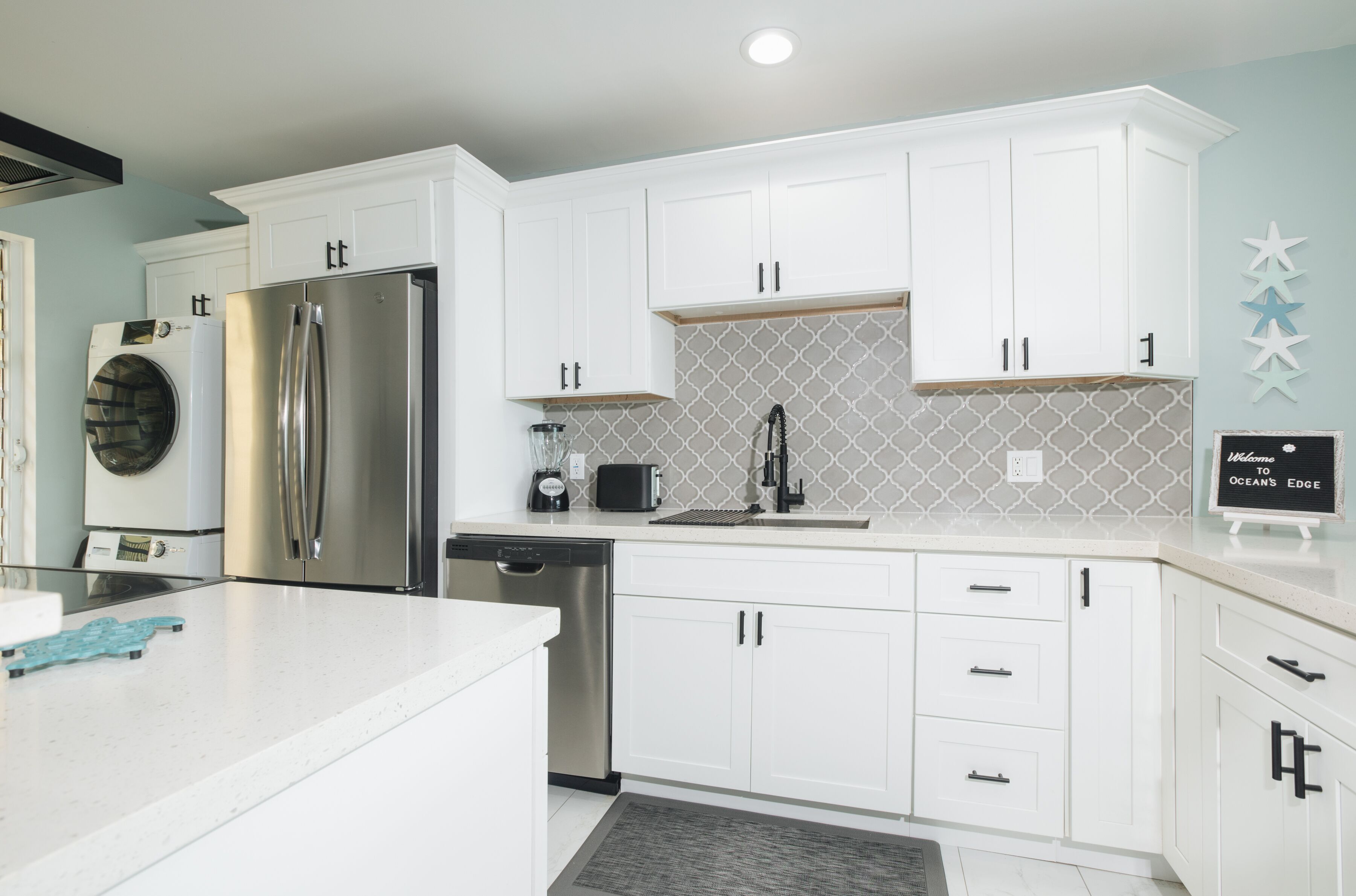 A modern kitchen with white cabinets, stainless steel appliances, and a tiled backsplash.