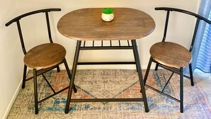 A small dining area with a round table and two chairs, a framed picture of Long Beach on the wall, and a patterned rug on the floor. - Spacious private studio in Long Beach (Long Beach)