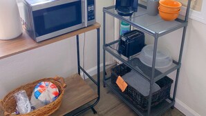 A kitchen area with a microwave, coffee maker, and shelves with kitchen supplies. - Spacious private studio in Long Beach (Long Beach)
