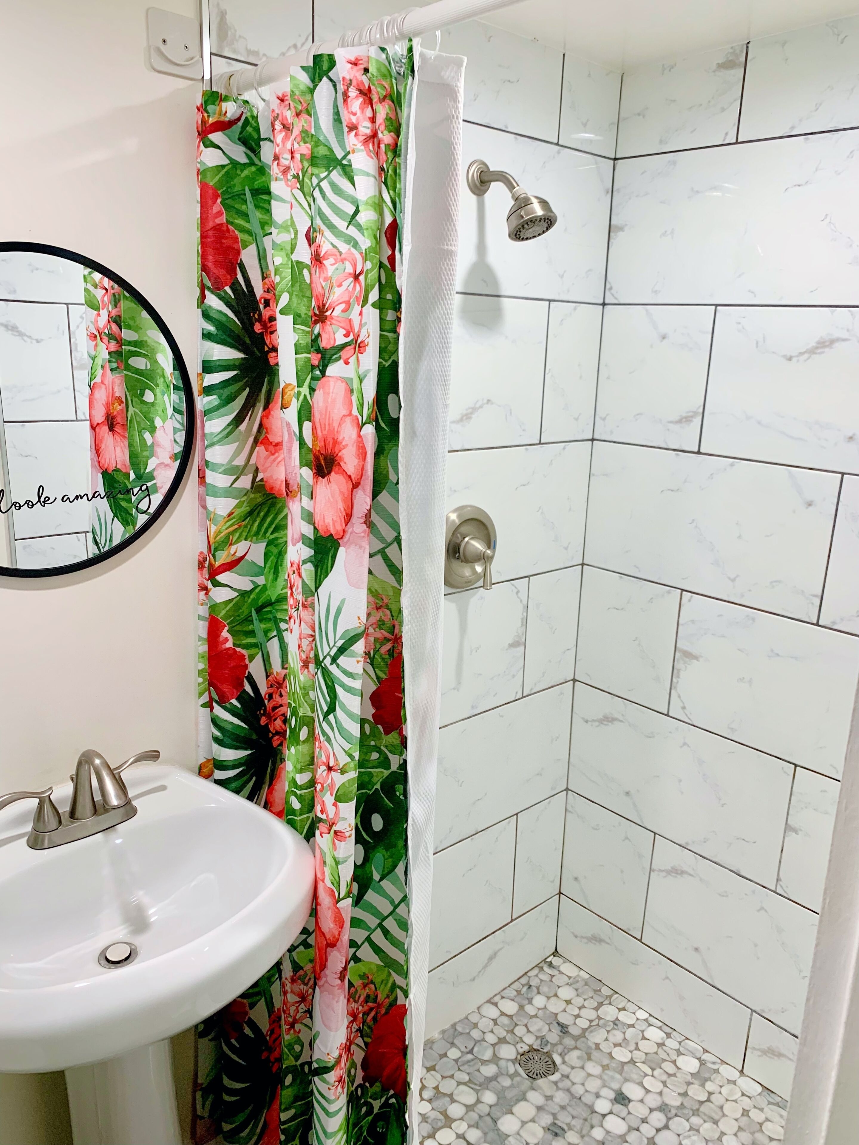 A bathroom with a shower, a sink, and a mirror.