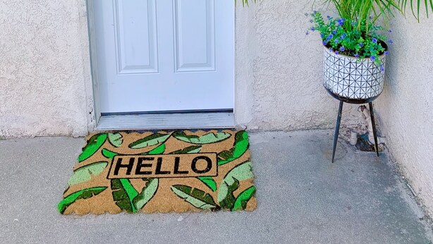 A white door with a keypad lock, a potted plant with green foliage, and a doormat with the word "HELLO". - Spacious private studio in Long Beach (Long Beach)