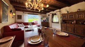 Un coin repas avec une table en bois dressée pour deux personnes, un canapé rouge et un lustre.