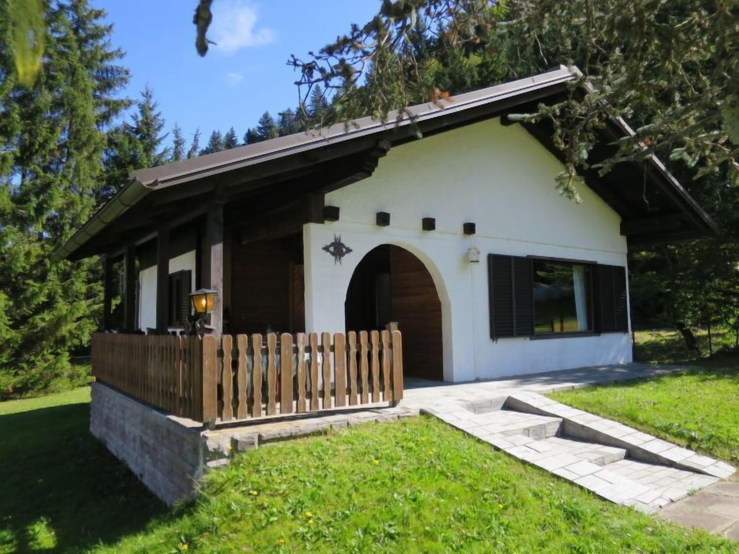 A small, single-story building with a sloped roof, a wooden porch, and a stone foundation.
