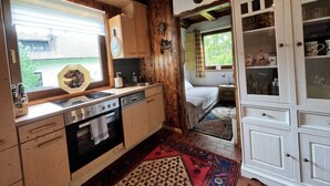 Une cuisine de taille réduite, dotée de meubles de rangement en bois, d’une cuisinière et d’une fenêtre avec des stores.