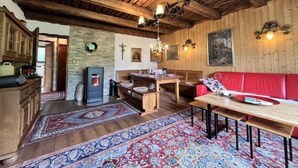 Un intérieur rustique en bois, avec un coin repas, un canapé rouge et une cheminée.