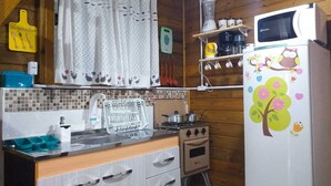 A kitchen with wooden cabinets, a stove, a sink, and a refrigerator with a floral design. - Your house in Floripa! (SC)