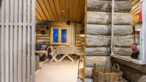 A log cabin interior with a cozy living area, a dining table, and a wicker basket.