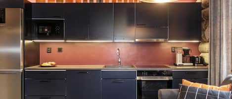 Een moderne keuken met donkere kastjes, een roestvrijstalen koelkast, een magnetron en een koffiezetapparaat.