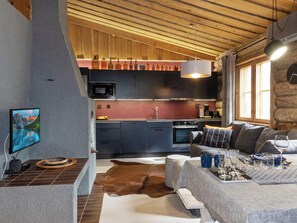 Een gezellige woonkamer met een flatscreen televisie, een bank en een eethoek met een tafel gedekt voor twee personen.