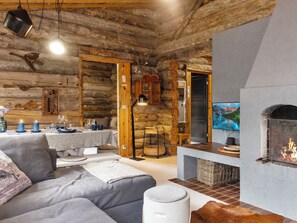 L’intérieur d’une cabane en rondins comprend un espace de vie, une table à manger, une cheminée et un téléviseur.