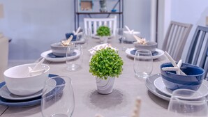 A dining table set with white and blue plates, bowls, and glasses, centered around a potted plant. - Better Together @ Edgewater Beach Resort Sleeps 10 (Panama City Beach)