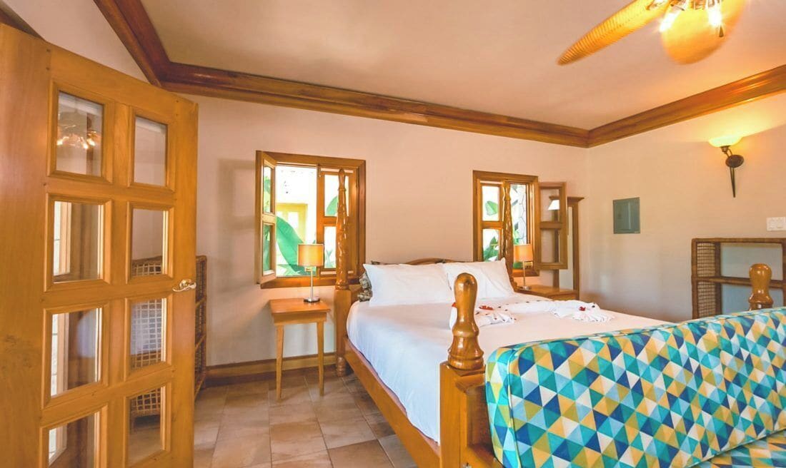 A bedroom with a bed, a wooden headboard, a nightstand, and a window with curtains.