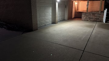 A garage with a white door, a concrete driveway, and a wooden fence.