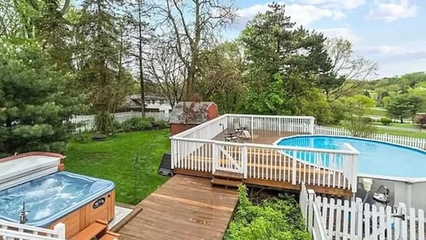 A backyard with a hot tub, a wooden deck, and a swimming pool surrounded by a white fence. - Comfortable private unit with hot tub, swimming pool and free parking (Gibsonia)