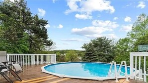 A wooden deck with a swimming pool, surrounded by trees and a white fence. - Comfortable private unit with hot tub, swimming pool and free parking (Gibsonia)