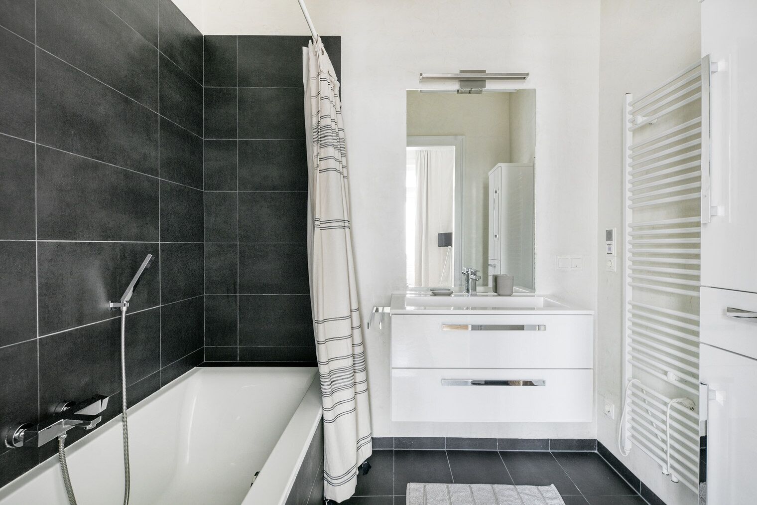 Une salle de bain moderne équipée d’une baignoire, d’une douche et d’un meuble-lavabo avec un miroir.