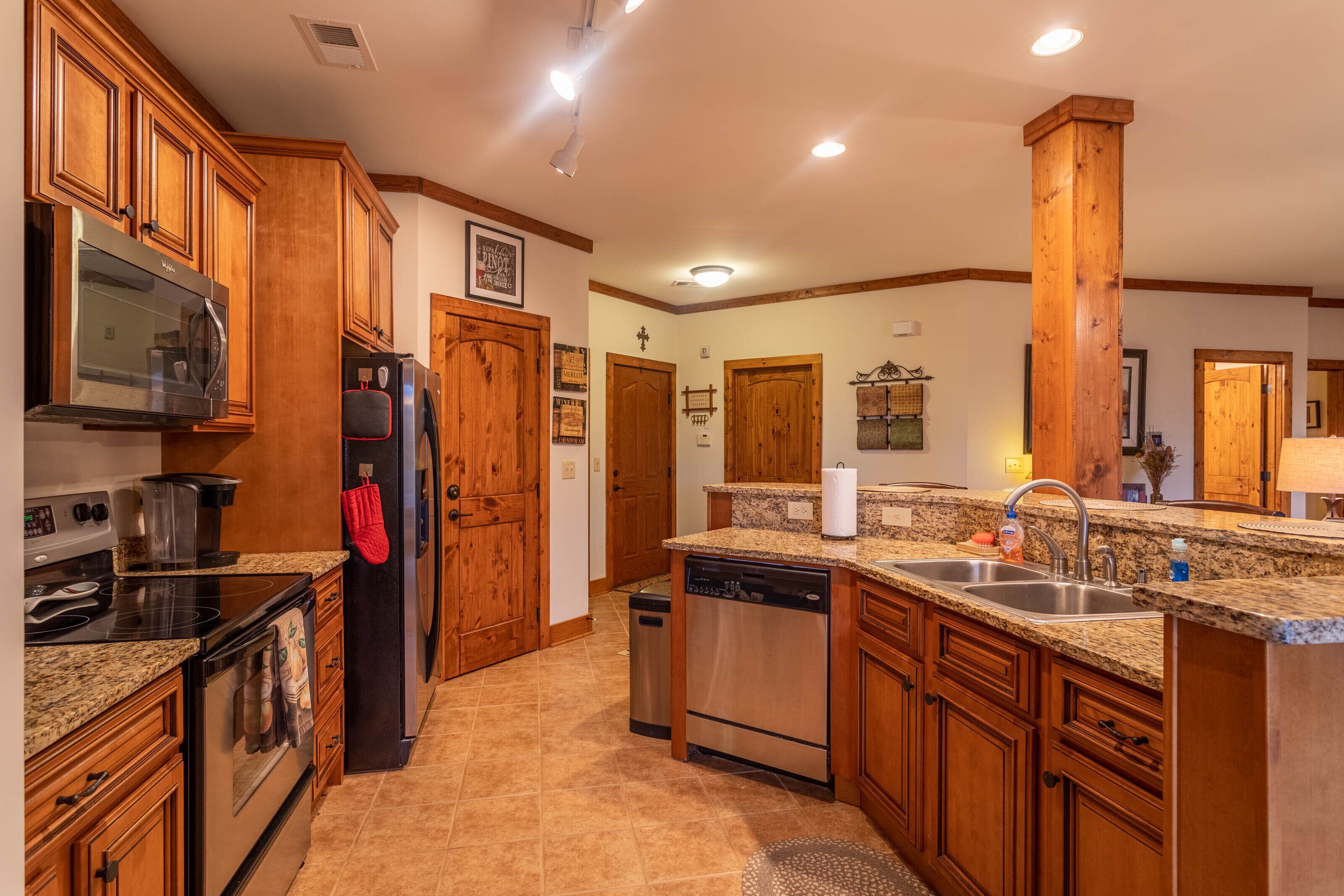 A modern kitchen with wooden cabinets, granite countertops, stainless steel appliances, and a central island with a sink.