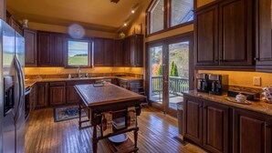 Une cuisine spacieuse avec des meubles de couleur bois foncé, un grand îlot central et une vue sur l’extérieur.