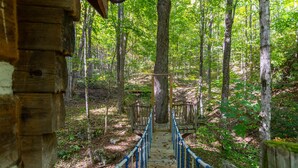 A wooden bridge in a forest with a rustic cabin on the left. - The Matney Ridge Estate- home with hot tub and firepit (Banner Elk)