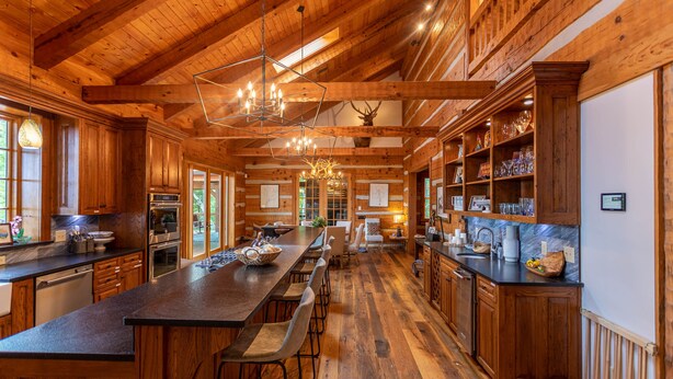 A spacious kitchen with wooden cabinets, a long island with bar stools, and a chandelier. - The Matney Ridge Estate- home with hot tub and firepit (Banner Elk)