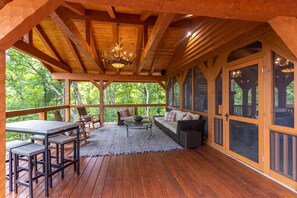 Relax in a cozy cabin setting with a spacious deck, comfortable seating, and stunning forest views.