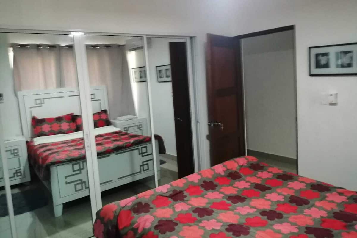 A bedroom with a bed, a wardrobe, a desk, and a chair.