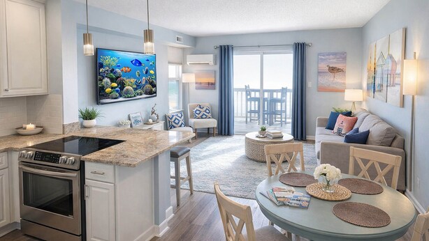 A modern kitchen with a built-in stove, a dining area with a round table and chairs, and a living room with a sofa and a TV.