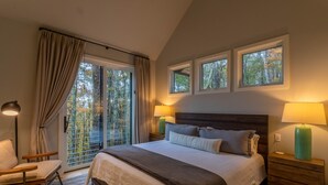 A bedroom with a large bed, two bedside lamps, a chair, a window with curtains, and a view of trees. - Four One Two Lodge at Eagles Nest, views, outdoor fireplace (Banner Elk)
