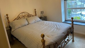 Ein Schlafzimmer mit Bett, Nachttisch und Fenster.