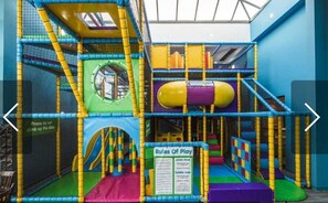 An indoor play area with various climbing structures and a slide.