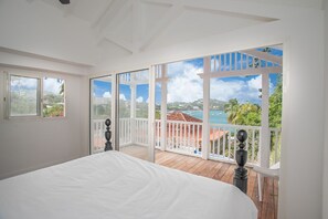 A bedroom with a large bed, a balcony with a view of the sea and greenery, and a white ceiling. - Manzelle & Mazurka ,up to 18 guests
Luxury beach front villa in Martinique  (Le François)