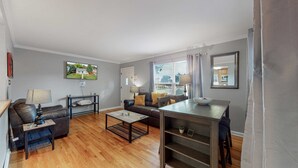 Una sala de estar con sofá, mesa de centro, televisión y mesa de comedor.