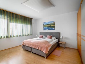A modern bedroom with a bed, a painting, and a window with curtains.