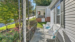 A covered porch with wicker furniture and a small American flag.