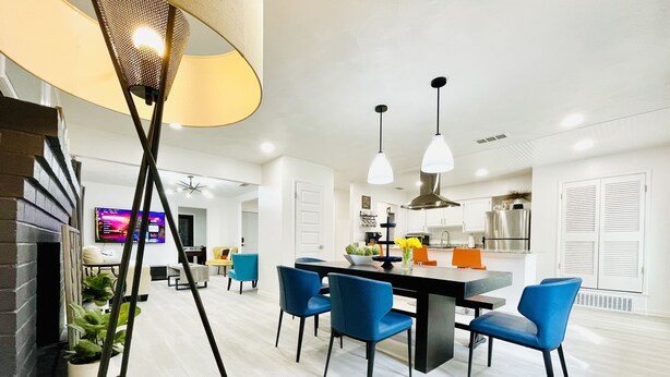 A modern kitchen with white cabinets, a dining area with blue chairs, and a TV mounted on the wall. - Walk to the AT&T Stadium, Texas Rangers Globe Life Park, Texas Live & many more. (Arlington)